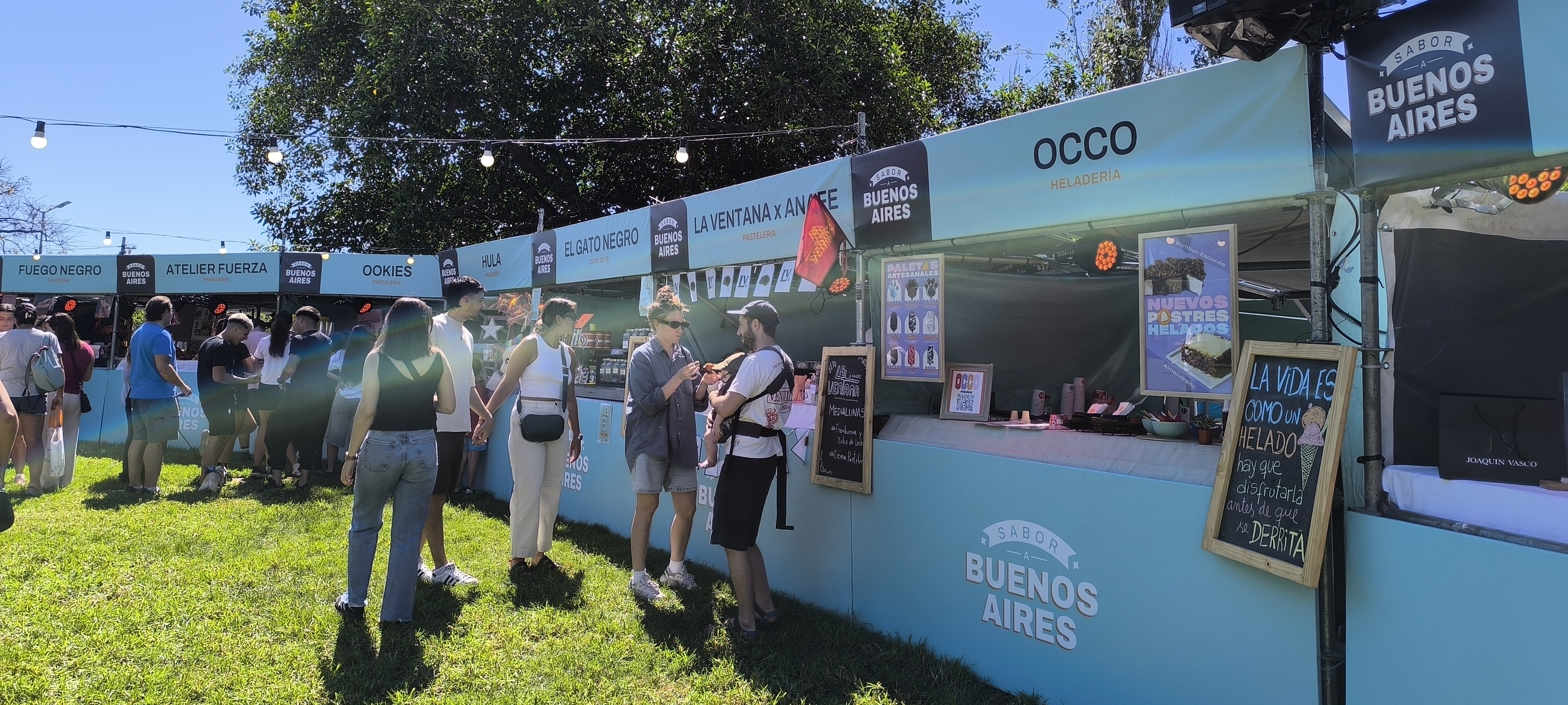 Personas comprando en los puestos de pastelería y café - Maia Coletto.